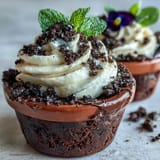 Rich chocolate brownies topped with fluffy cream and crumbled Oreo dirt in festive pots.