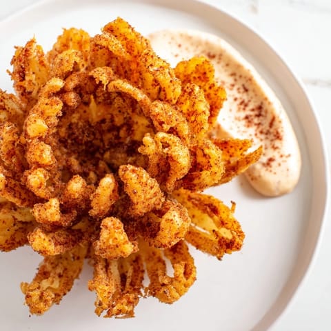 Golden, crispy Blooming Onion served with a creamy sauce, ready to be enjoyed as a savory appetizer.