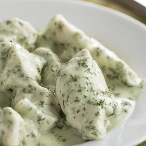 Green Goddess Chicken Salad featuring tender herb-infused chicken on a bed of greens, topped with sliced cucumber and a drizzle of dressing.  