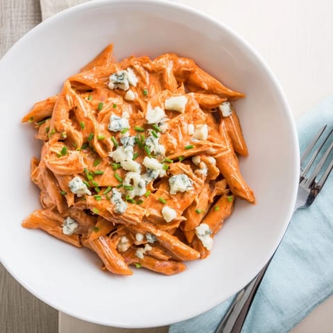 Forkful of Buffalo Chicken Pasta with tender shredded chicken, creamy sauce, and a sprinkle of blue cheese crumbles.  