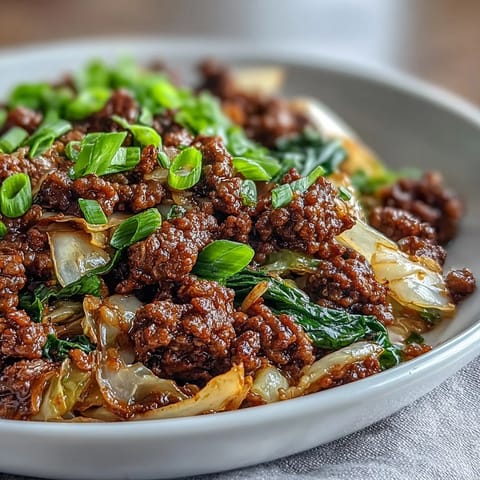 Forkful of savory Chinese Ground Beef and Cabbage Stir-Fry served steaming hot, garnished with green onions and sesame seeds over a bed of white rice.