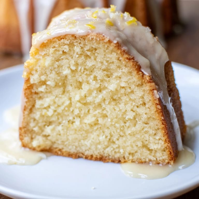 A slice of homemade Lemon Pound Cake, showcasing a tender crumb and drizzled lemon icing, delicious.