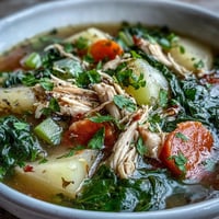A steaming bowl of Collard Greens, Chicken and Vegetable Soup with tender shredded chicken, diced potatoes, and bright greens in a savory broth.  
