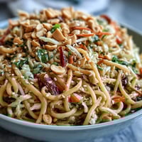 Creamy peanut noodle bowl with crisp vegetables and a rich sesame dressing, perfect for a quick vegetarian meal.  