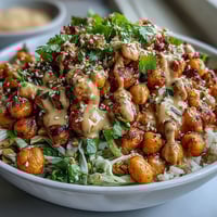 Colorful Peanut Chickpea Protein Bowl with roasted chickpeas, fresh vegetables, and creamy peanut sauce drizzled on top.  
