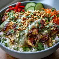 Vibrant Thai peanut chicken bowl with tender chicken, coconut rice, crisp vegetables, and creamy spicy peanut sauce.