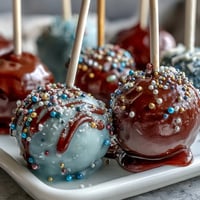 Graduation cake pops in school colors with gold sprinkles, arranged in a festive display for a graduation party.
