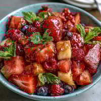 A vibrant bowl of strawberry lemonade fruit salad with fresh berries, grapes, and pineapple, tossed in a tangy lemon-honey dressing.