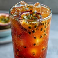 Tropical Sunrise Mocktail with vibrant passionfruit-orange layers, glistening with ice.